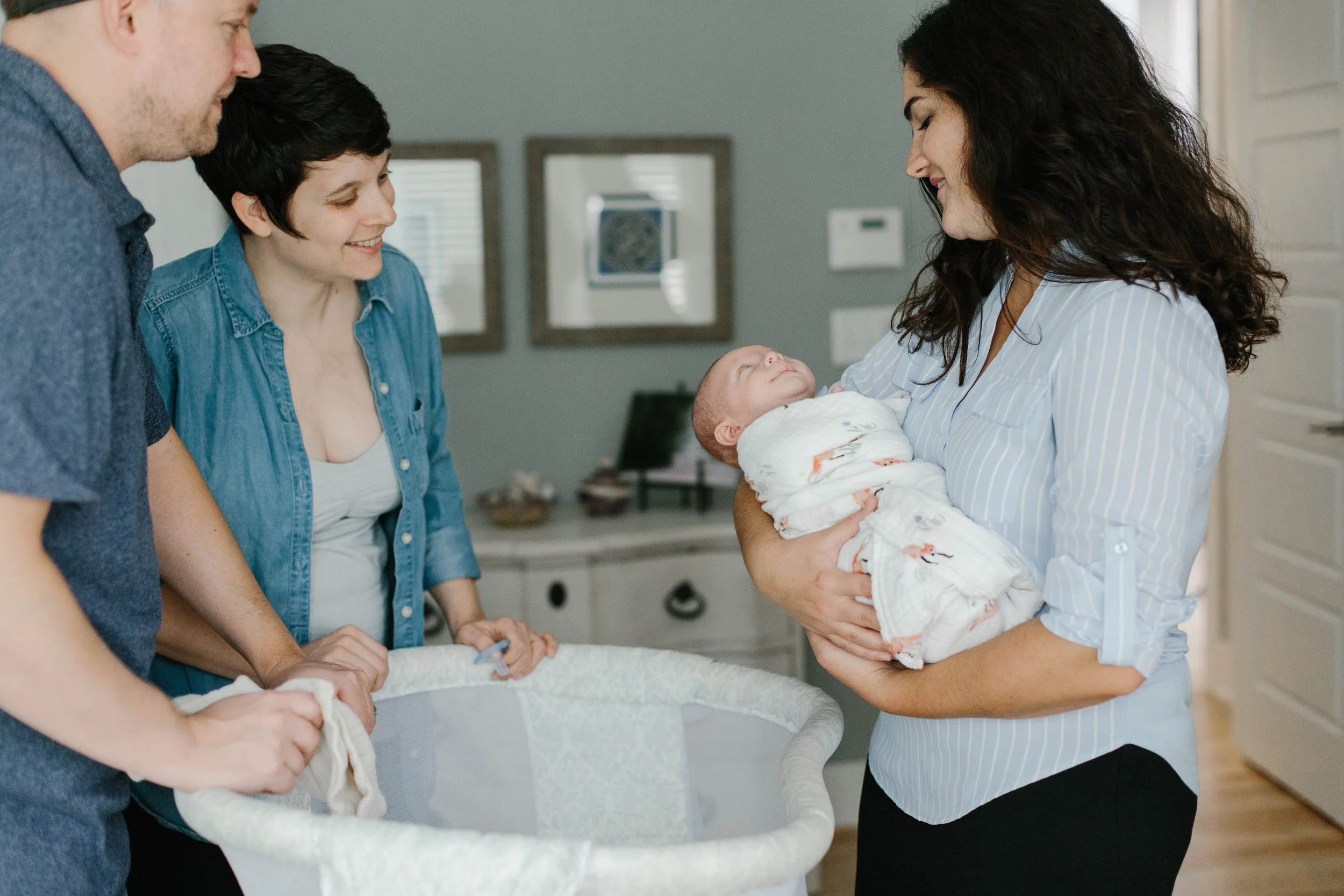 newborn care specialist holding swaddled baby in nursery during bottle introduction