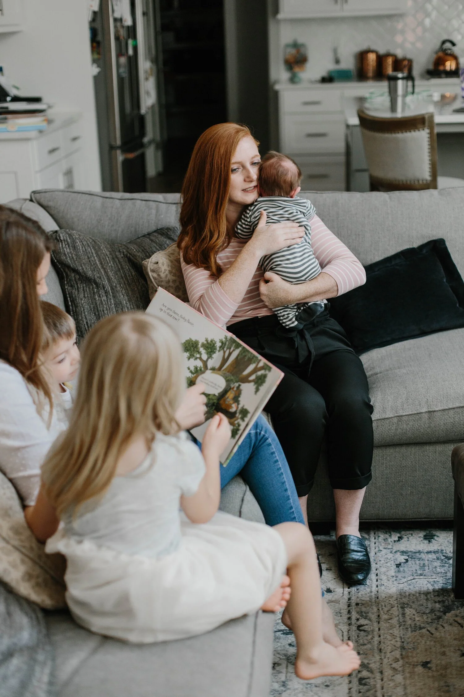 caregiver holding newborn while children enjoy story time supporting development