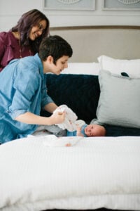 Newborn care specialist gently swaddling a newborn on a bed during an overnight care shift