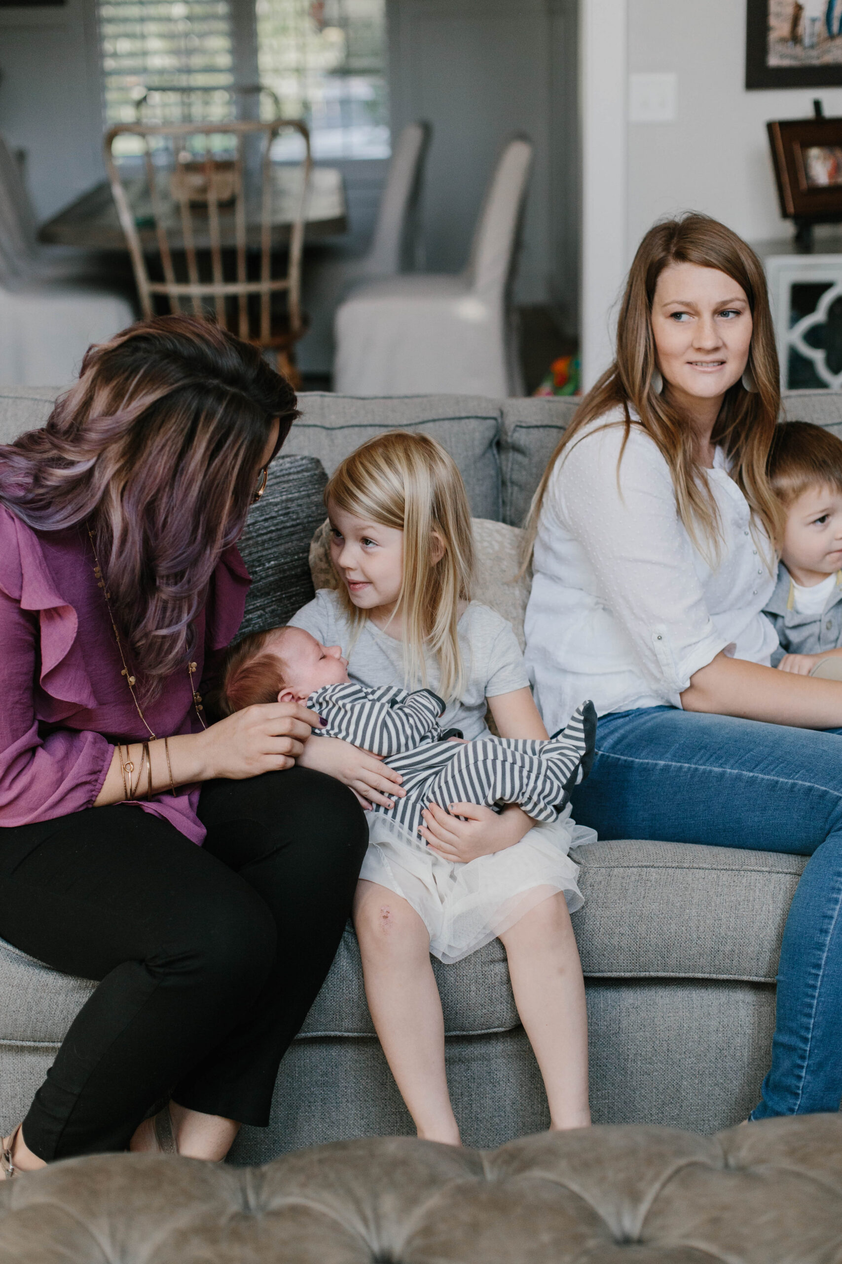 older sibling holding newborn while family provides dads postpartum support