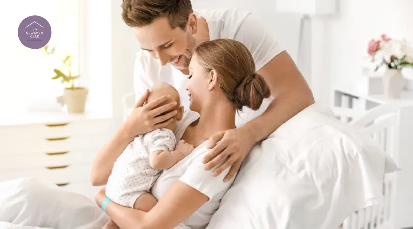 Parents cuddling their newborn while bonding together in a bright postpartum bedroom